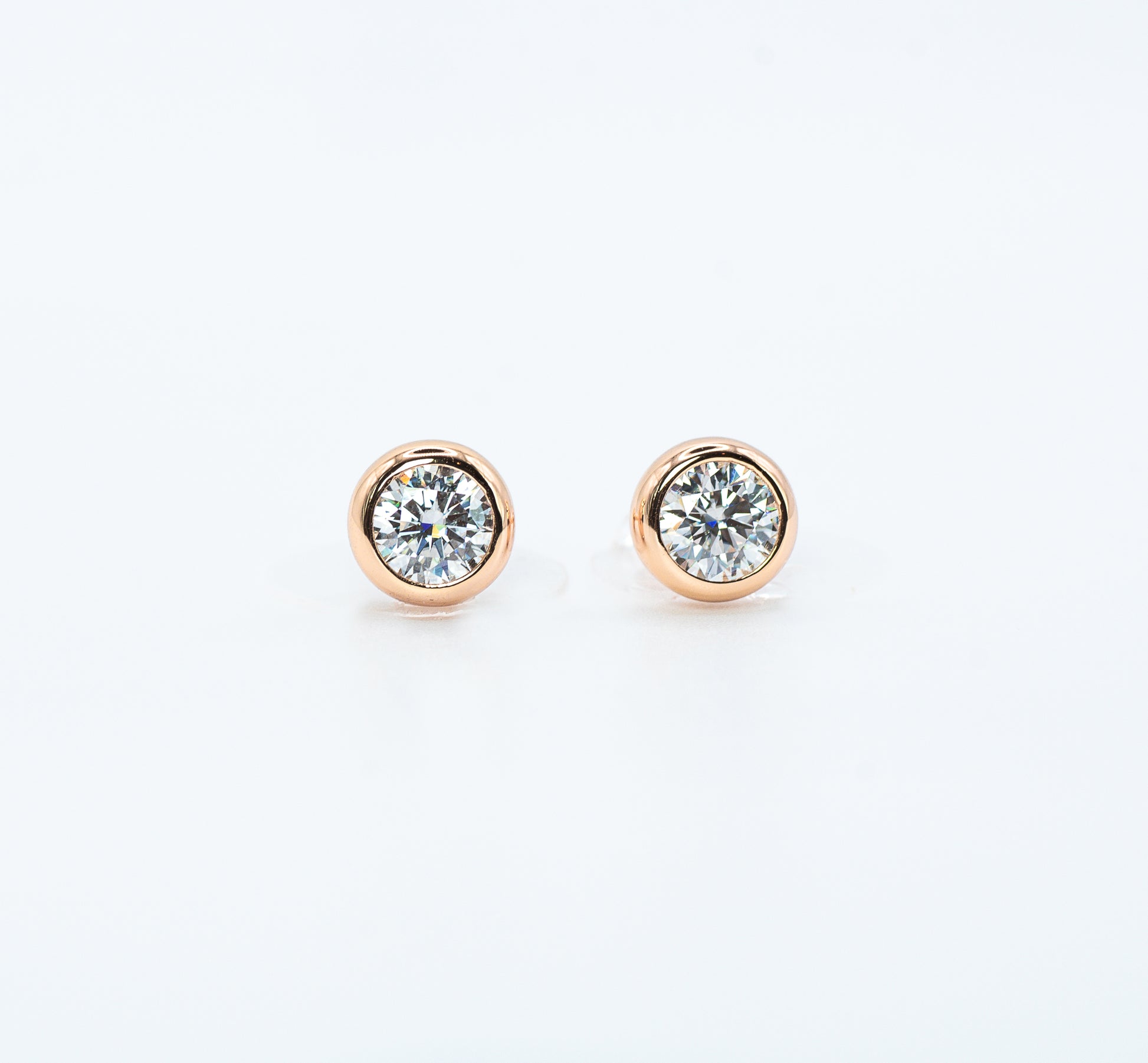 Pair of rose gold color with  Cubic Zirconia stud earrings on a white background