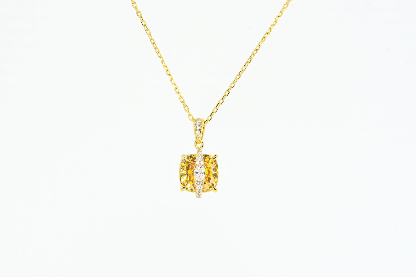 Gold color necklace with a yellow gemstone pendant on a white background