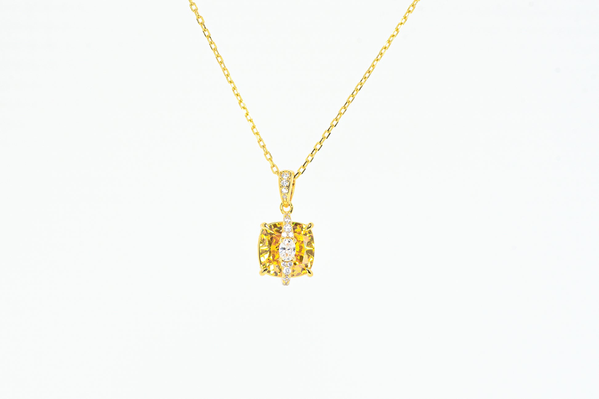 Gold color necklace with a yellow gemstone pendant on a white background