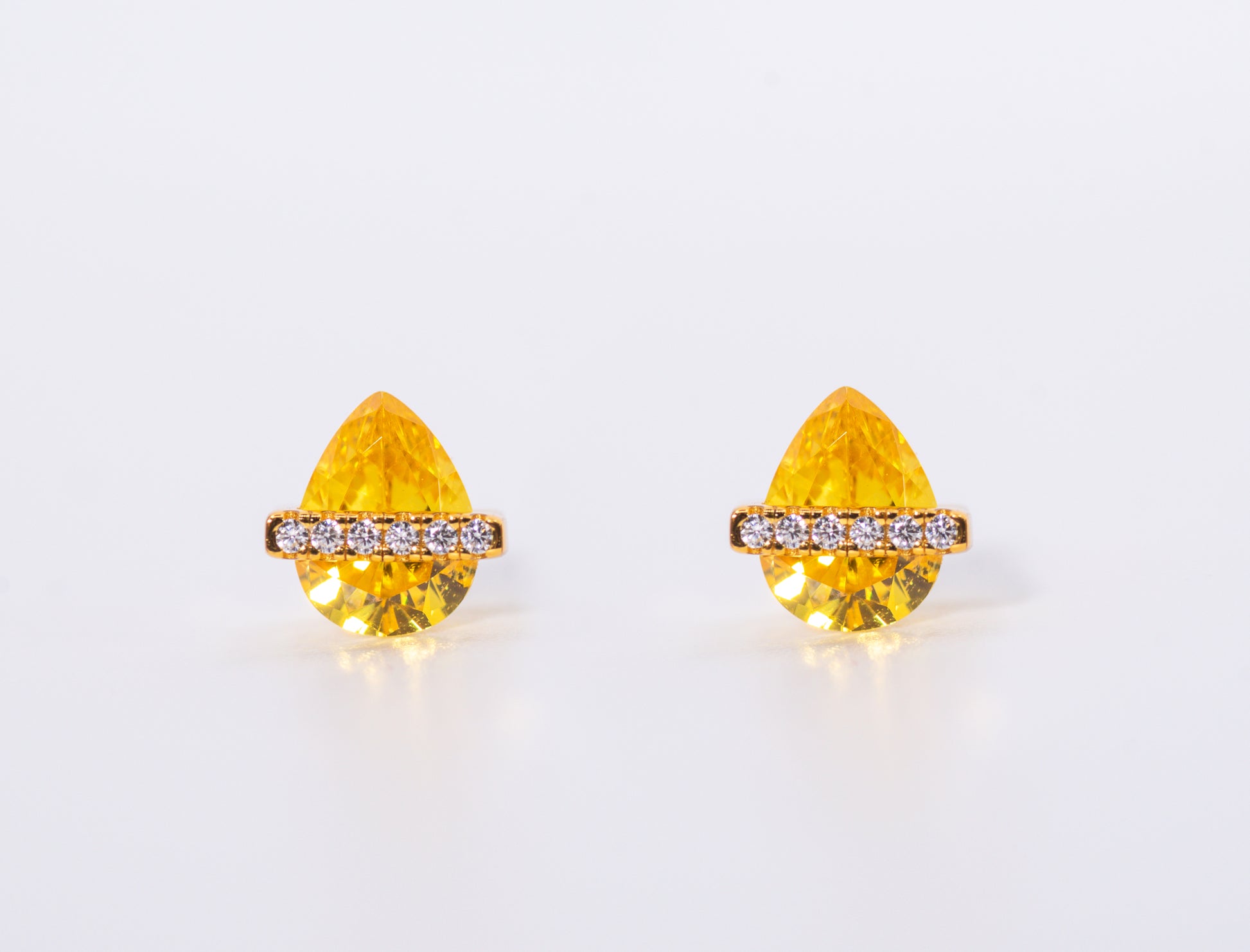Pair of yellow teardrop-shaped earrings with gold accents on a white background