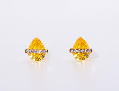 Pair of yellow teardrop-shaped earrings with gold accents on a white background