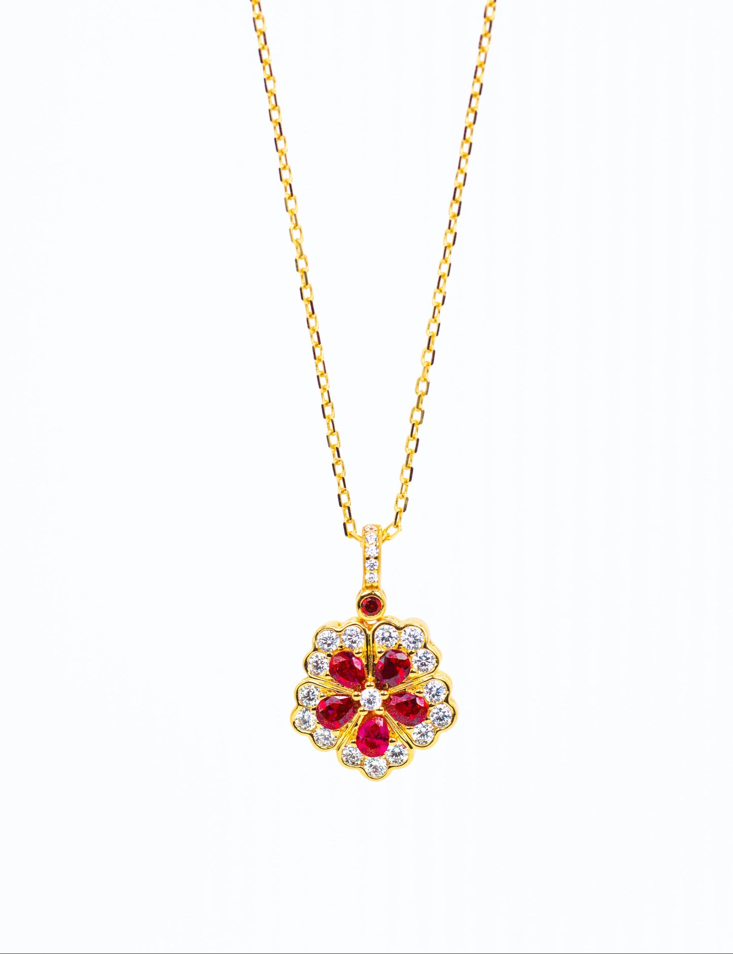 Gold necklace with a red gemstone pendant on a white background