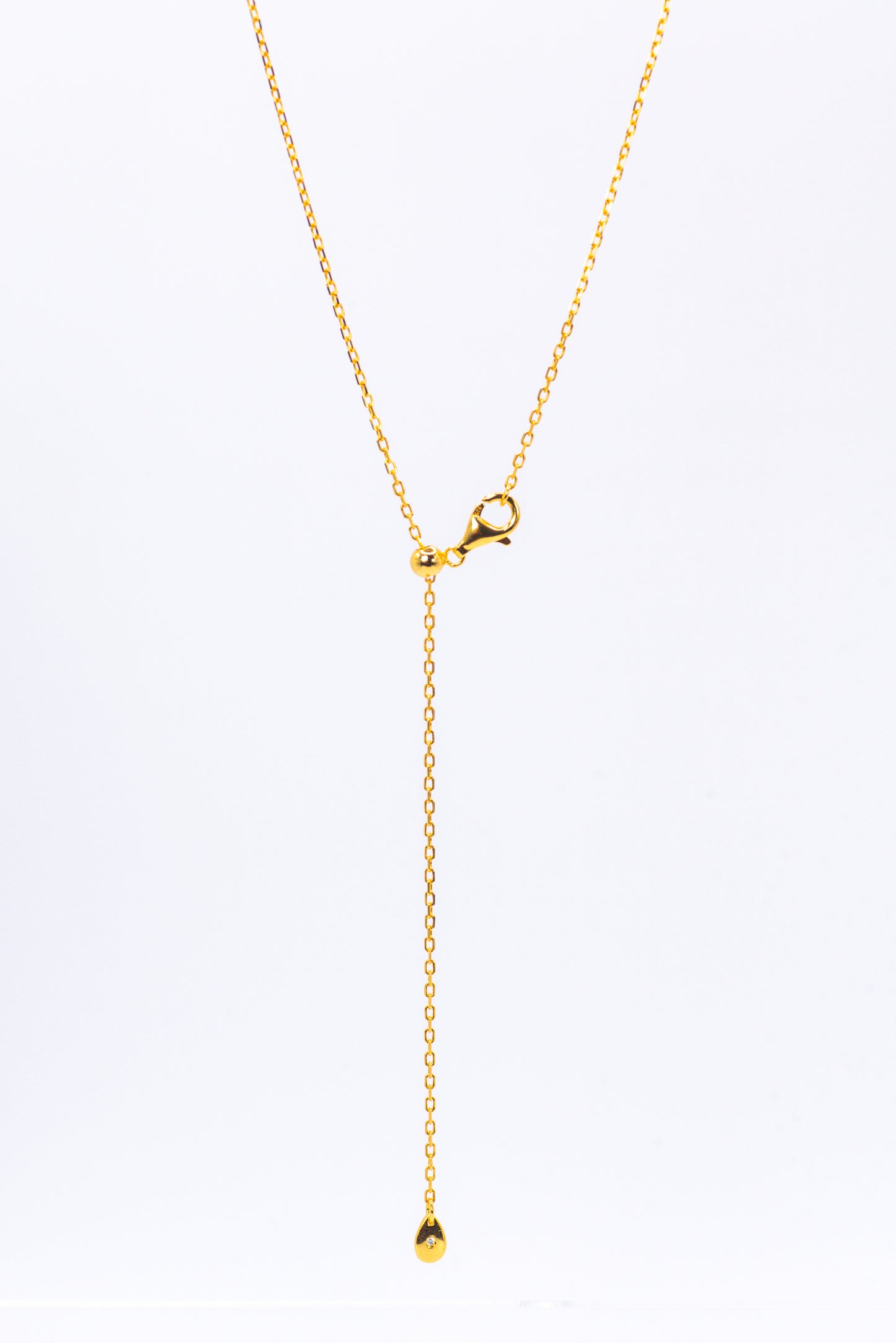 Gold necklace with a small pendant on a white background