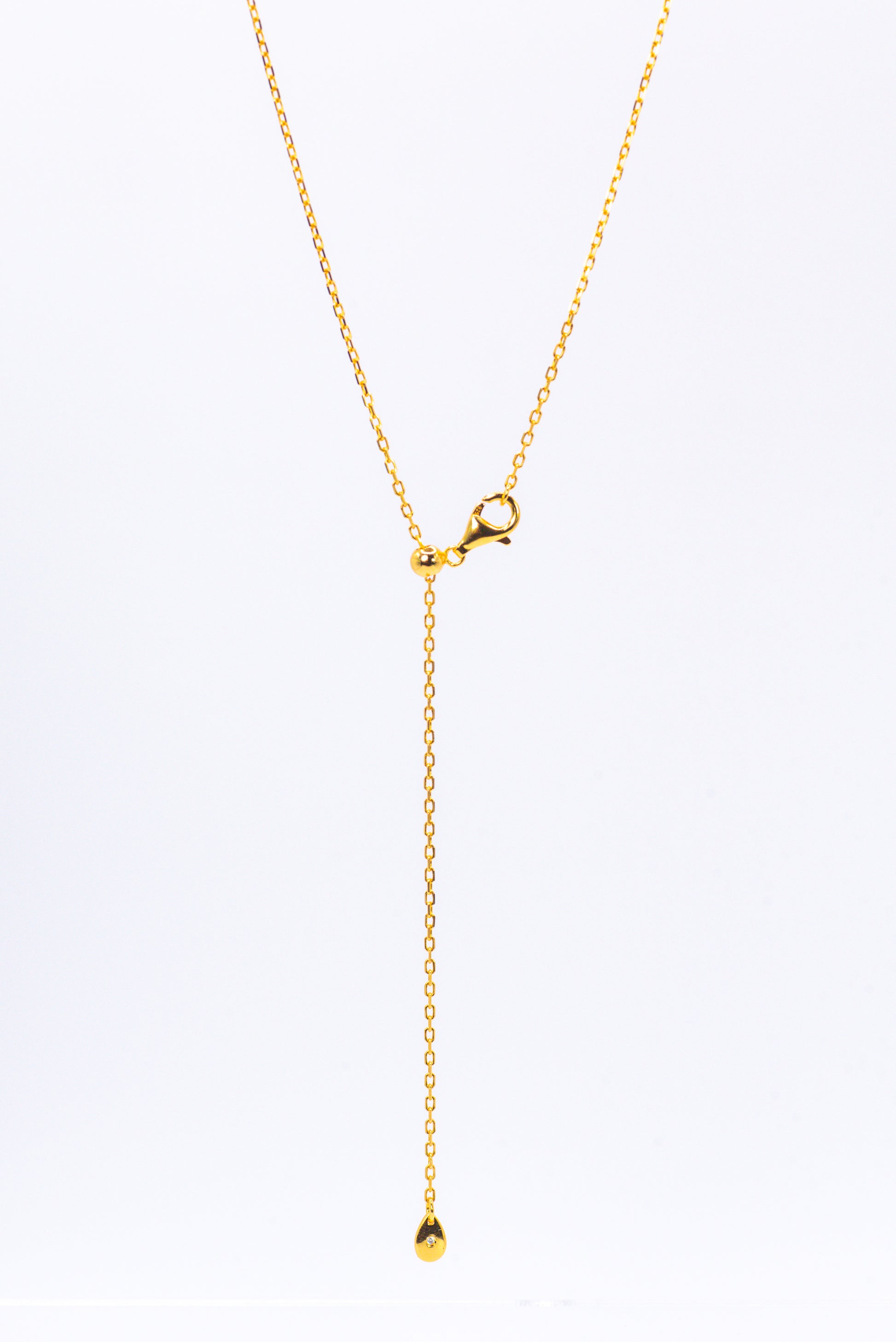Gold necklace with a small pendant on a white background