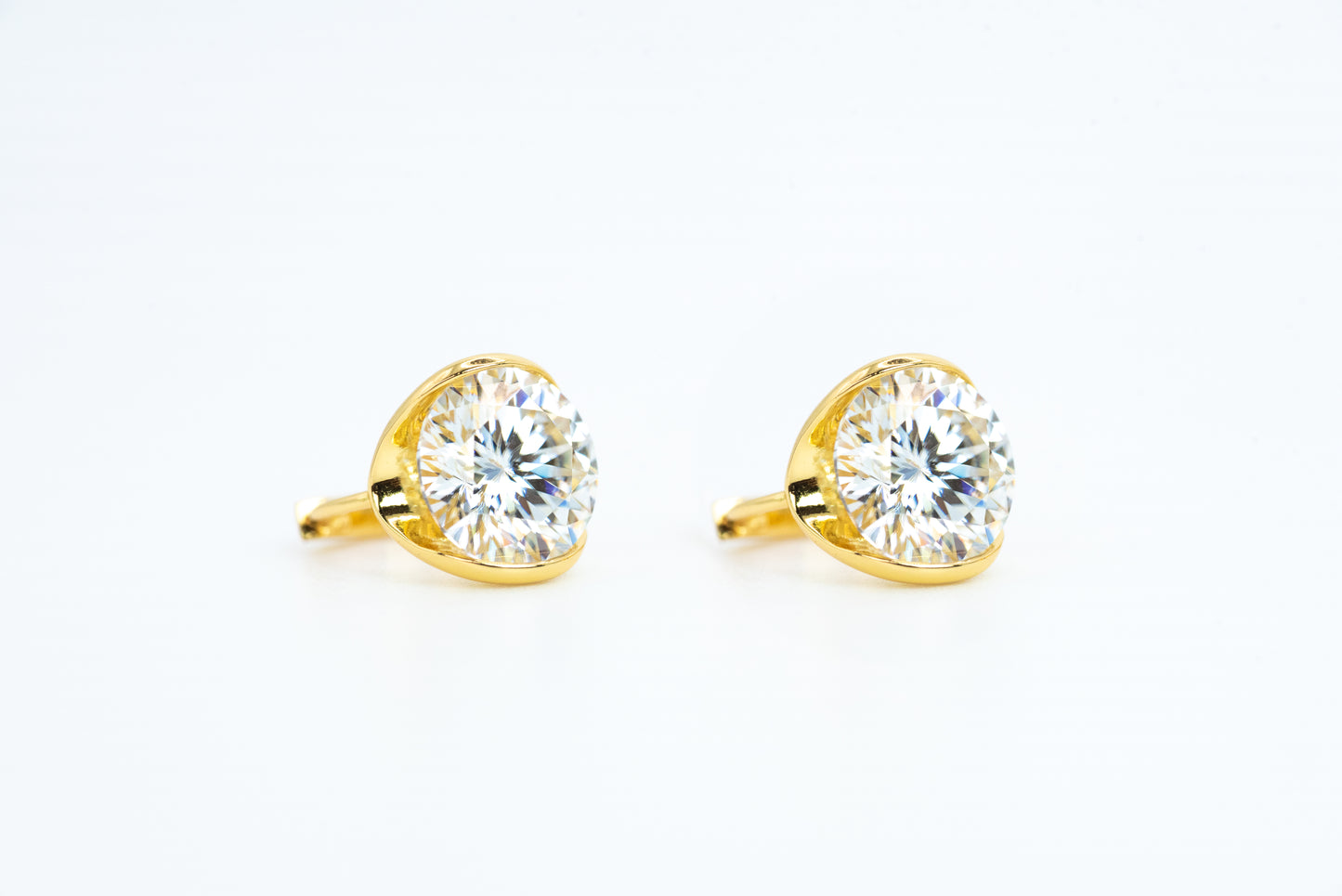 Gold earrings with clear gemstones on a white background