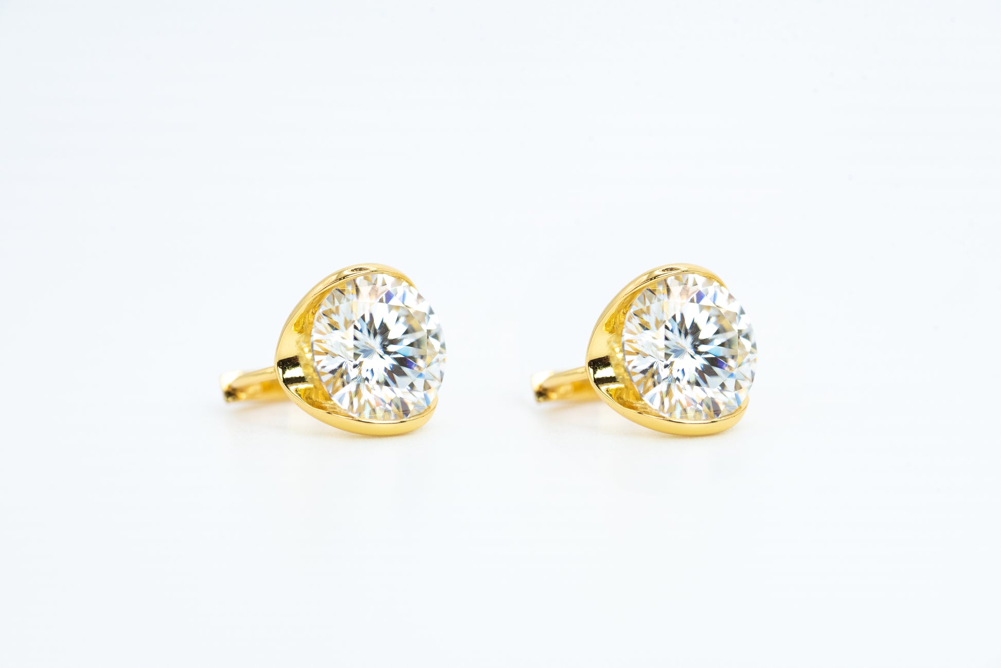 Gold earrings with clear gemstones on a white background