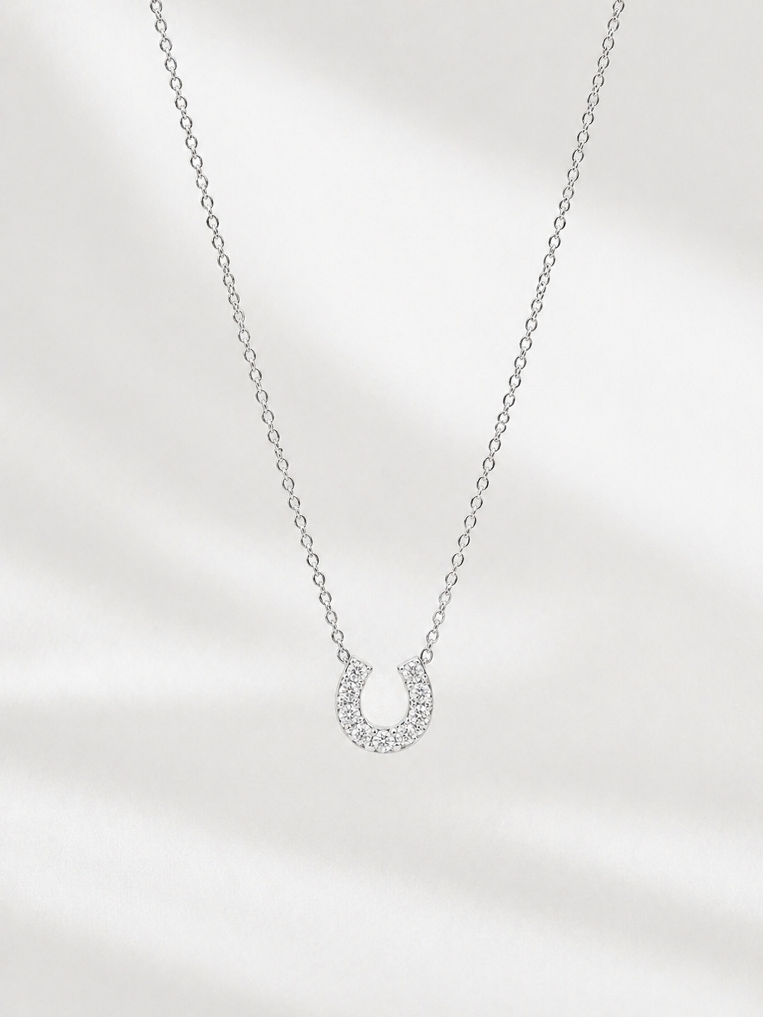Silver necklace with a small pendant on a light gray background