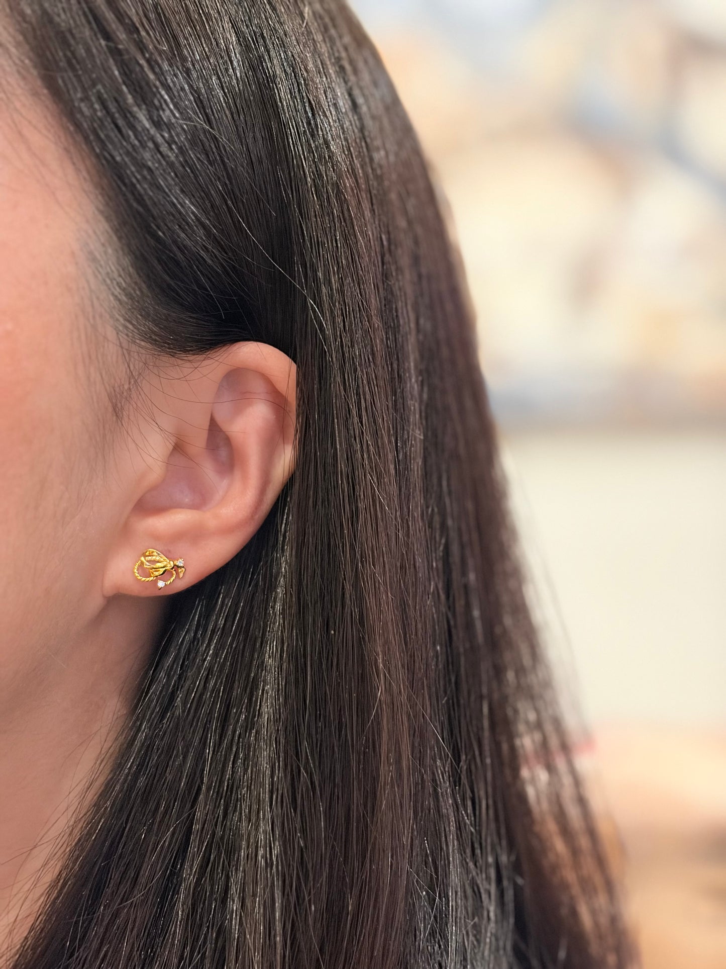 Close-up of a person wearing a gold earring with a blurred background