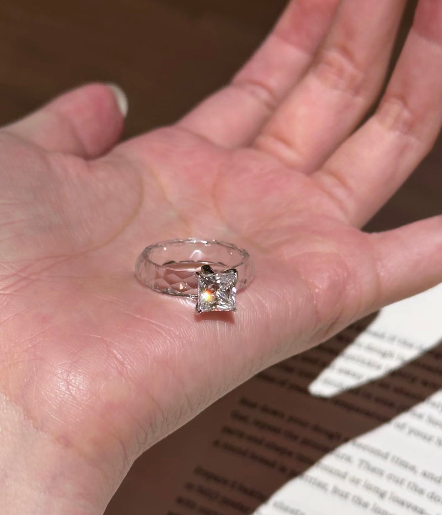 Silver ring with a clear gemstone on a person's hand