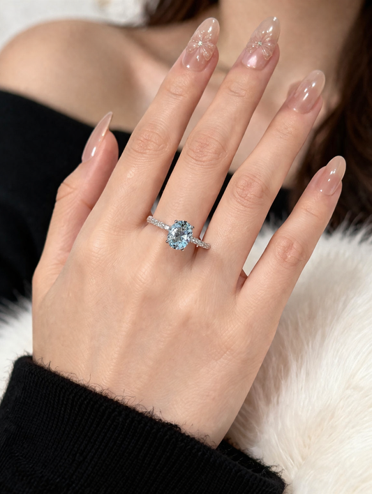 Hand wearing a silver ring with a blue gemstone on a white fur background
