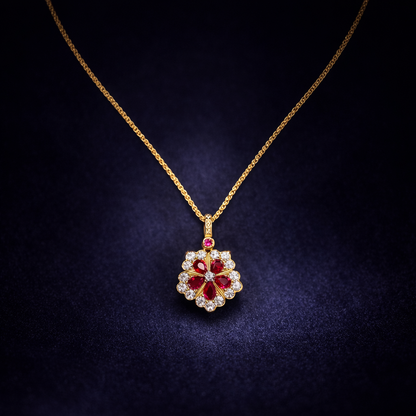 Gold necklace with a floral pendant featuring red gemstones on a dark background