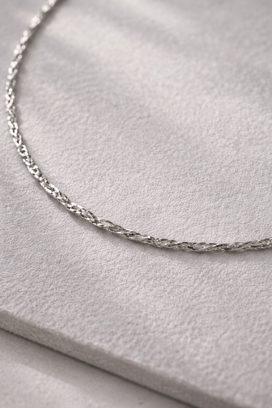 Silver chain necklace on a light gray surface