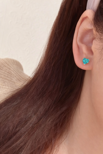 a girl wearing a blue heart earrings