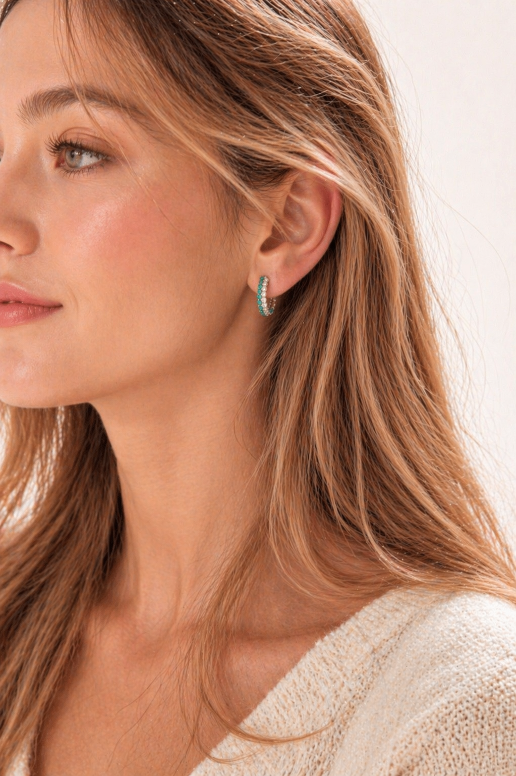 Close-up of a woman wearing a silver hoop earring with a light background