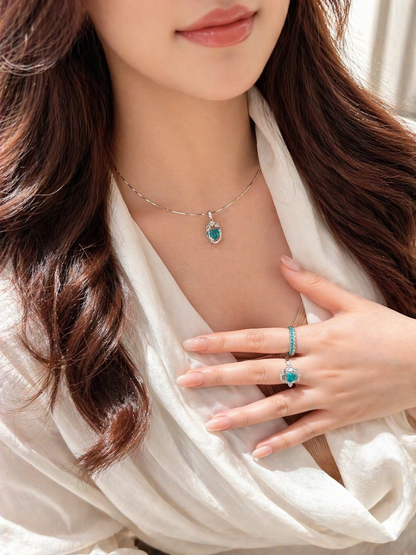 Close-up of a woman wearing a necklace and ring with a blue gemstone.