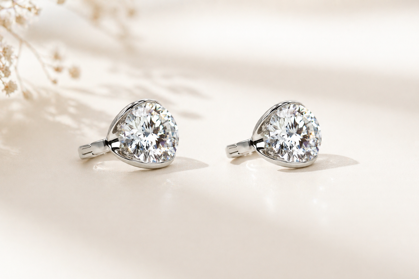 Pair of diamond earrings on a soft beige background