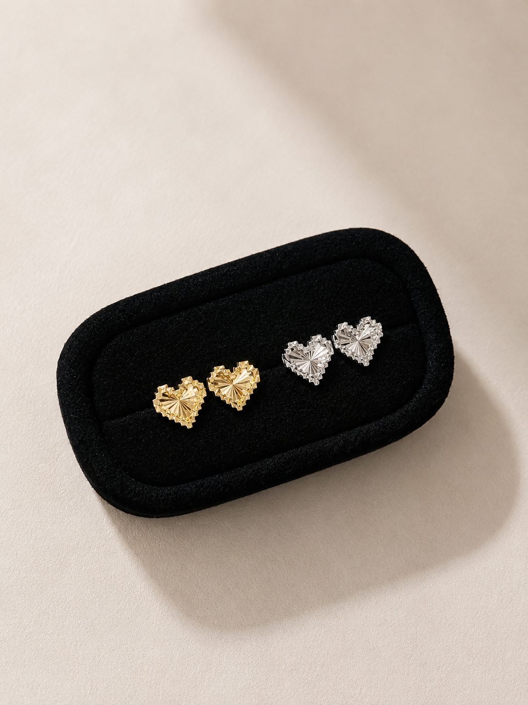 Pair of heart-shaped earrings in a black jewelry case on a beige background