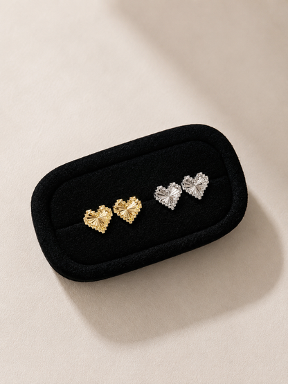 Pair of heart-shaped earrings in a black jewelry case on a beige background