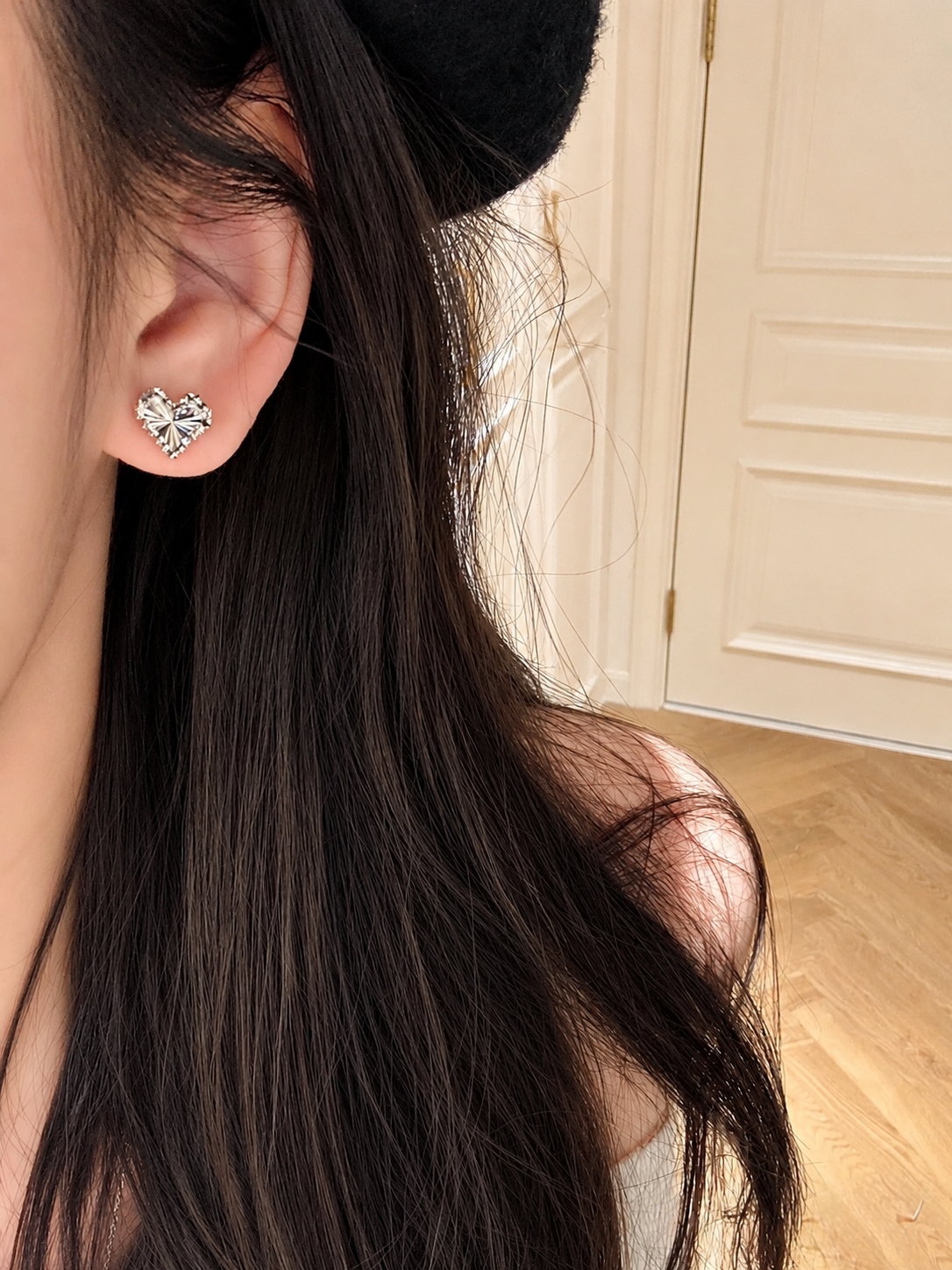 Heart-shaped earrings worn by a person with long dark hair.