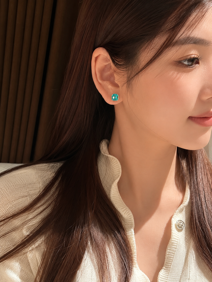 Lab-grown Paraiba cushion-cut stud earrings by Lunelle Atelier, featuring vibrant blue-green gemstones on a sleek silver setting.