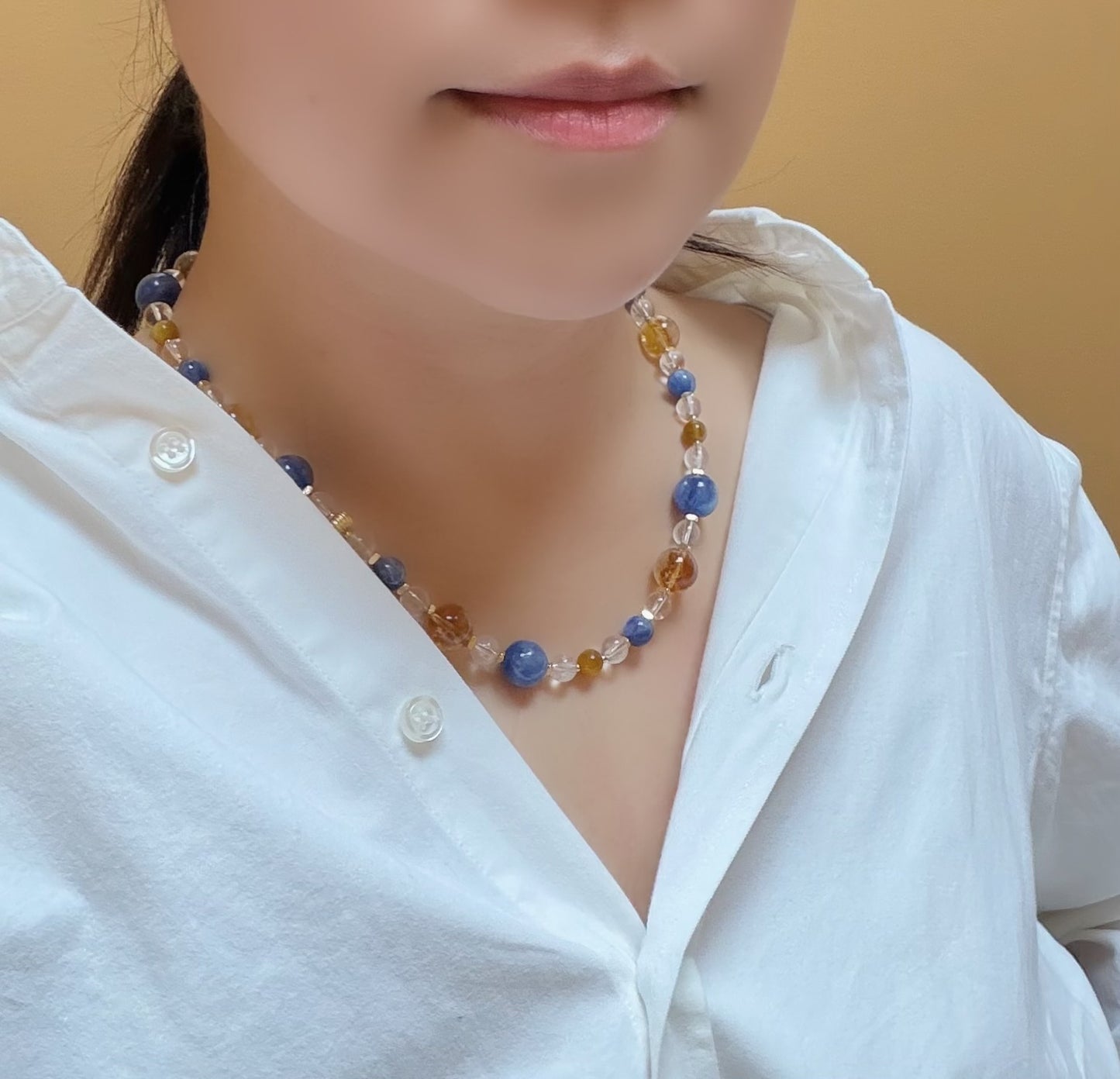 Person wearing a colorful beaded necklace with a plain background
