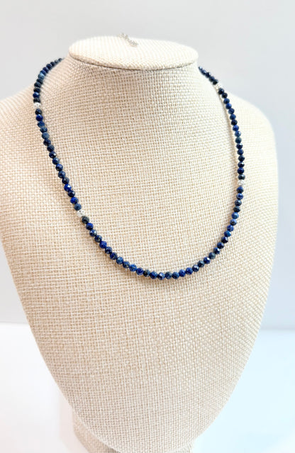 Blue beaded necklace on a white mannequin bust against a light gray background
