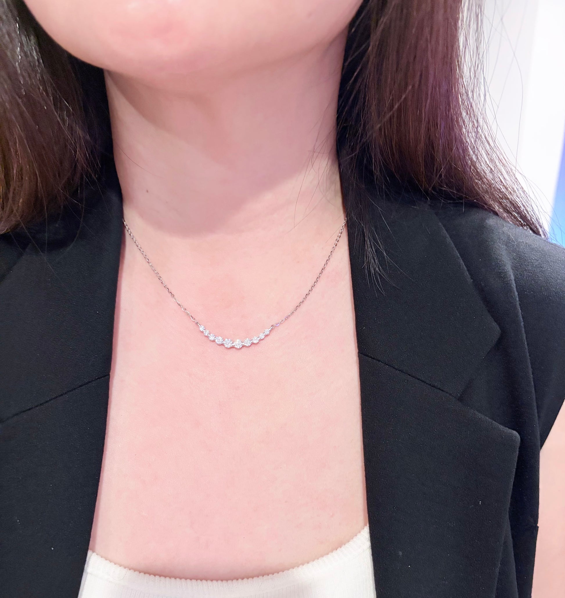 Person wearing a delicate necklace with a plain background