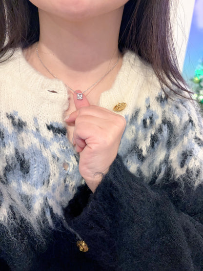Person wearing a necklace with a square shape gemstone pendant, holding it up to the camera.
