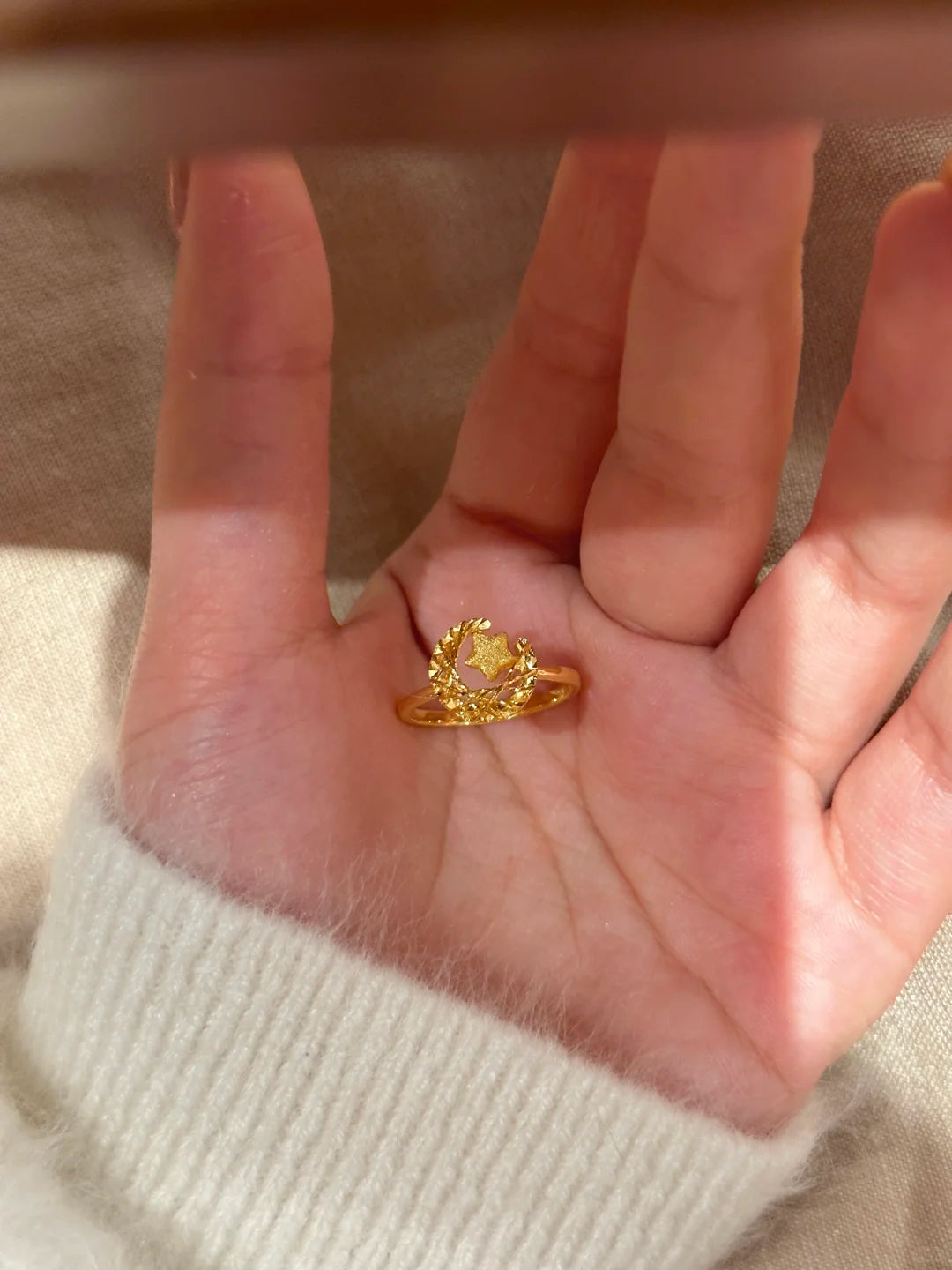 Gold ring on a person's finger with a neutral background