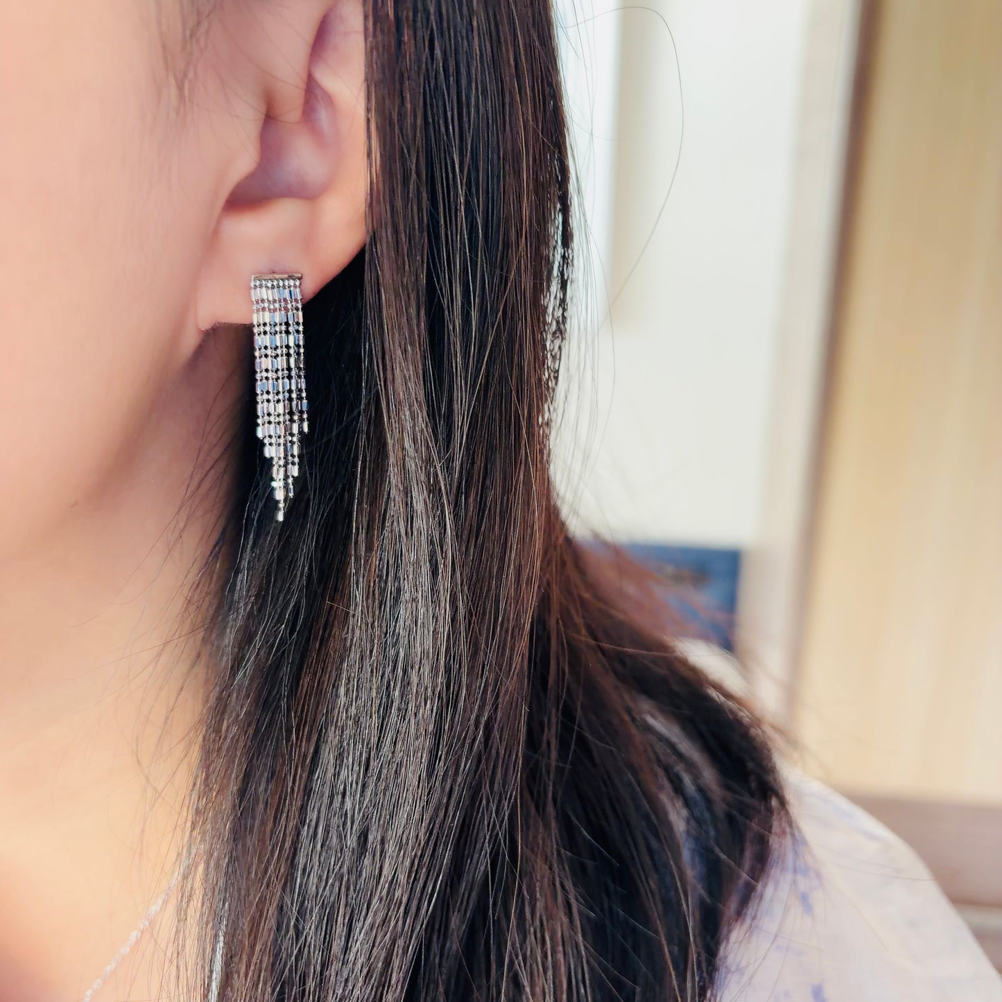 Close-up of a silver earring worn by a person with long dark hair.