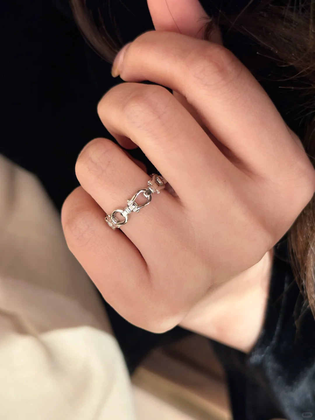 Close-up of a hand wearing a silver ring with a unique design.