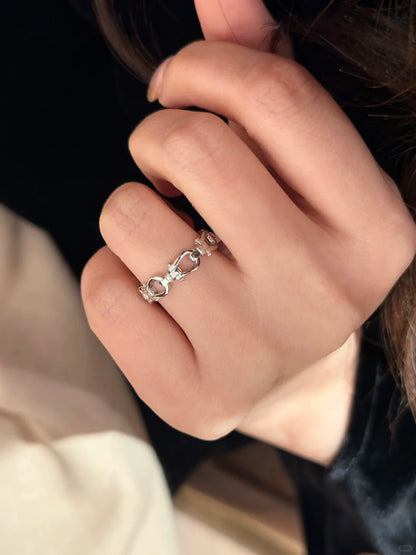 Close-up of a hand wearing a silver ring with a unique design.