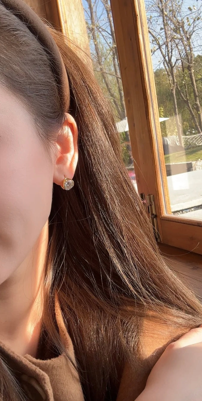 Close-up of a person wearing earrings with a window and outdoor view in the background