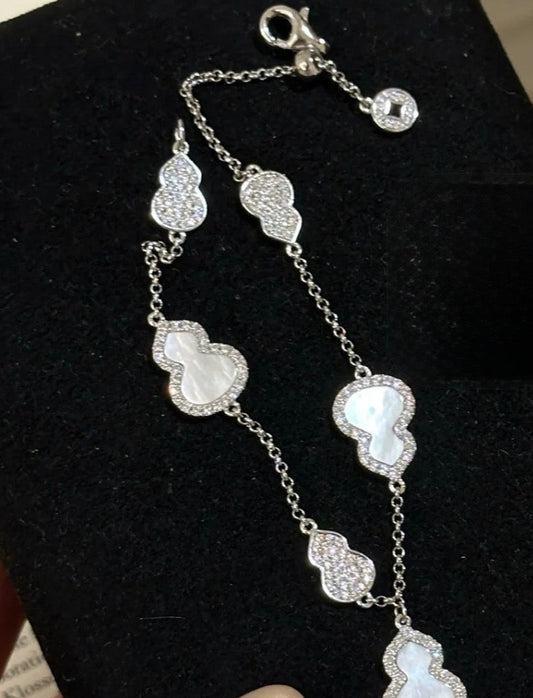 Silver necklace with heart-shaped pendants on a black display card held by a hand.