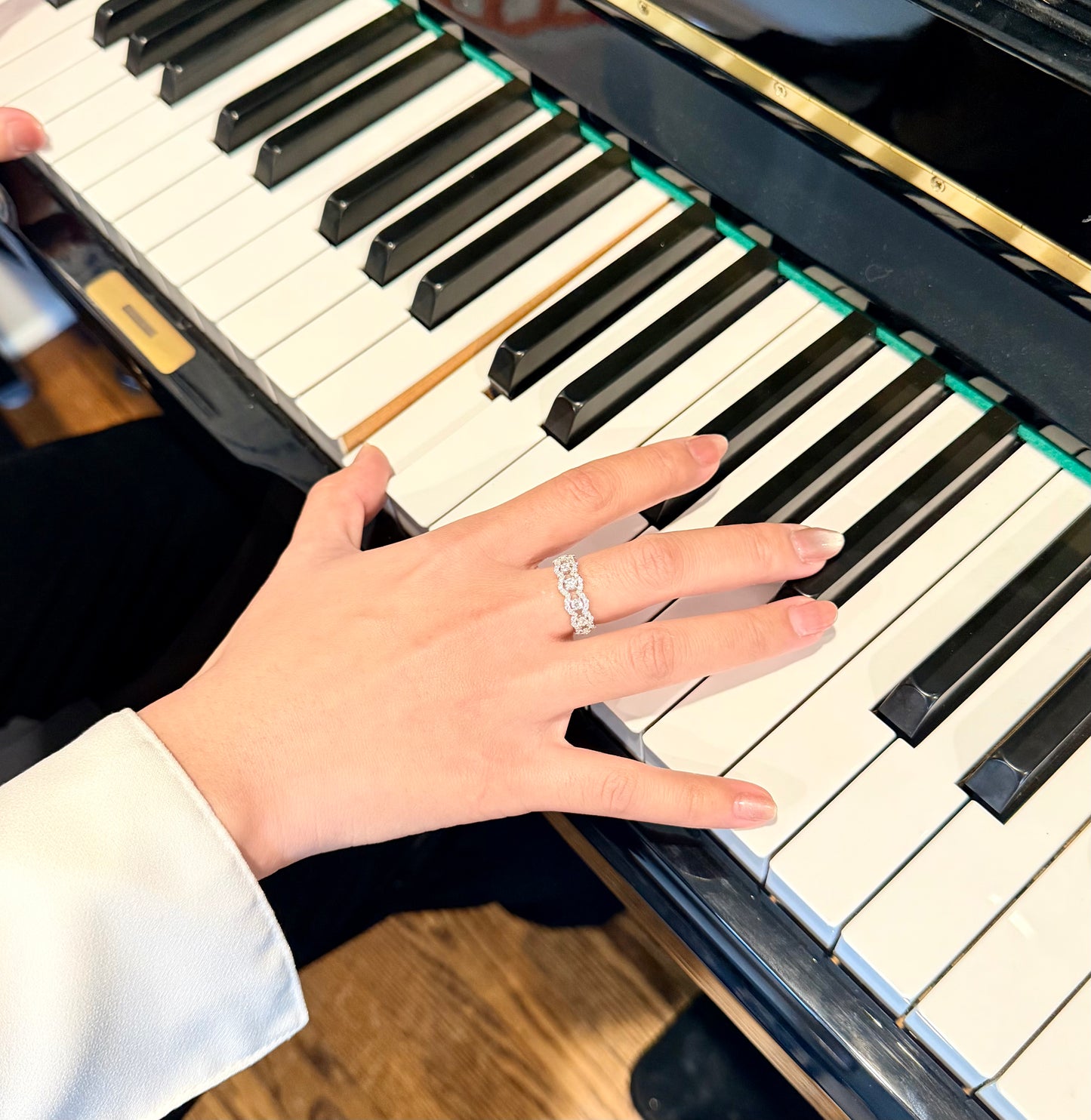 Hand playing a piano with a ring on the finger