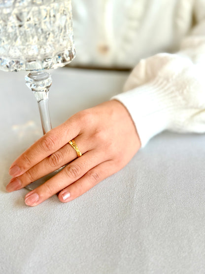 Hand with a gold ring holding a crystal glass on a light background