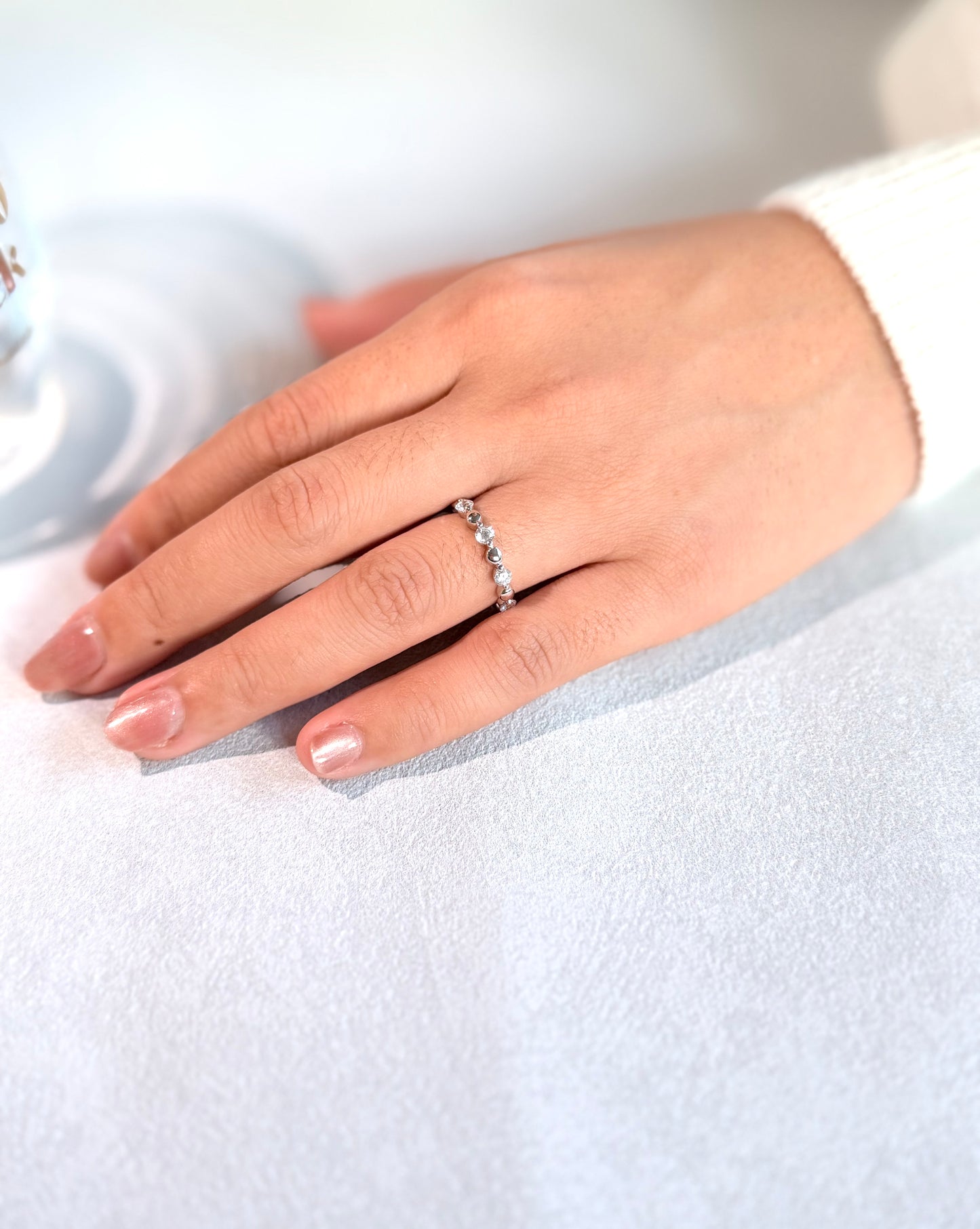 Close-up of a hand wearing a diamond ring on a light background