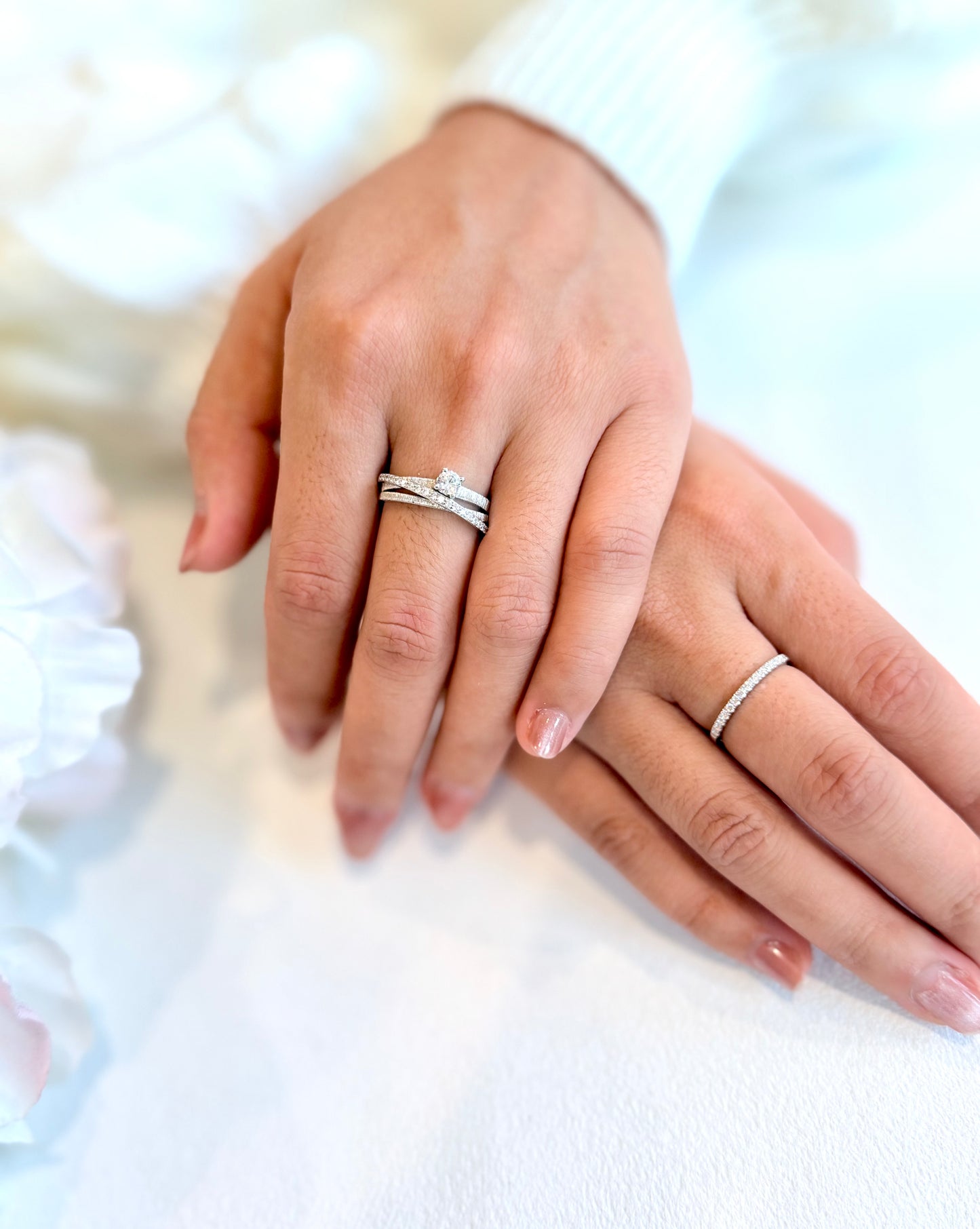 Close-up of two hands wearing silver rings on a blurred background