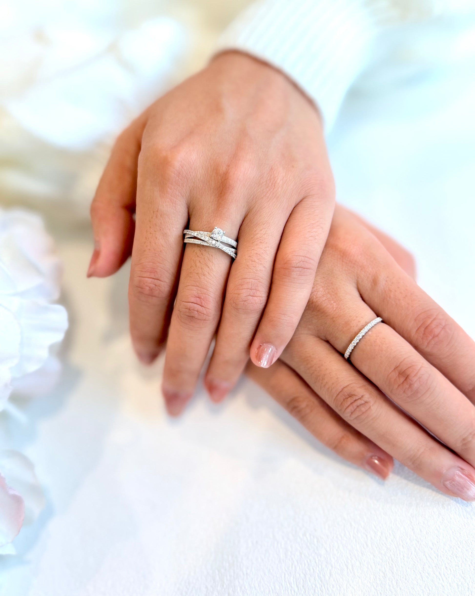 Close-up of two hands wearing silver rings on a blurred background