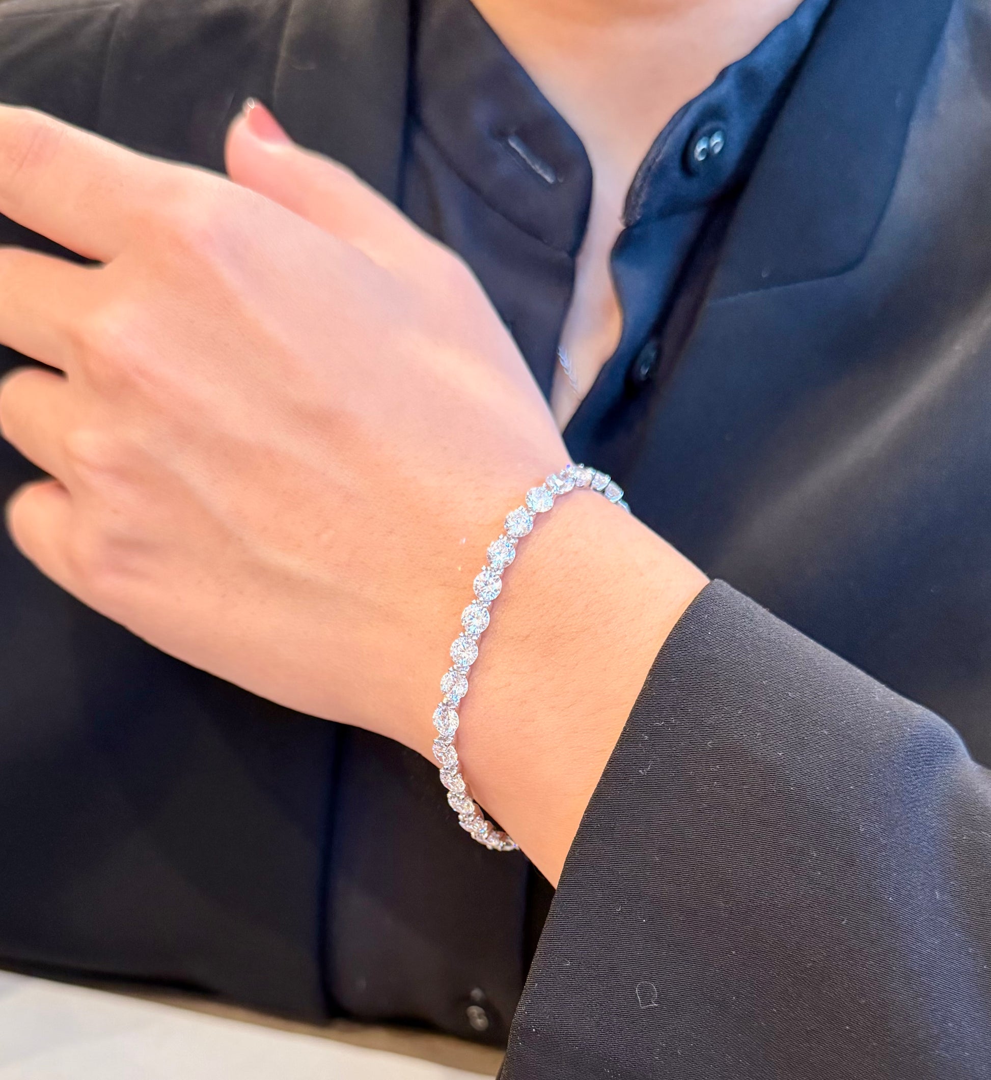 Person wearing a silver bracelet on a plain background