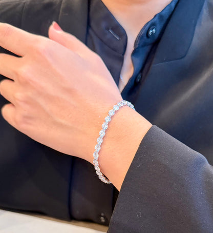 Person wearing a silver bracelet on a plain background