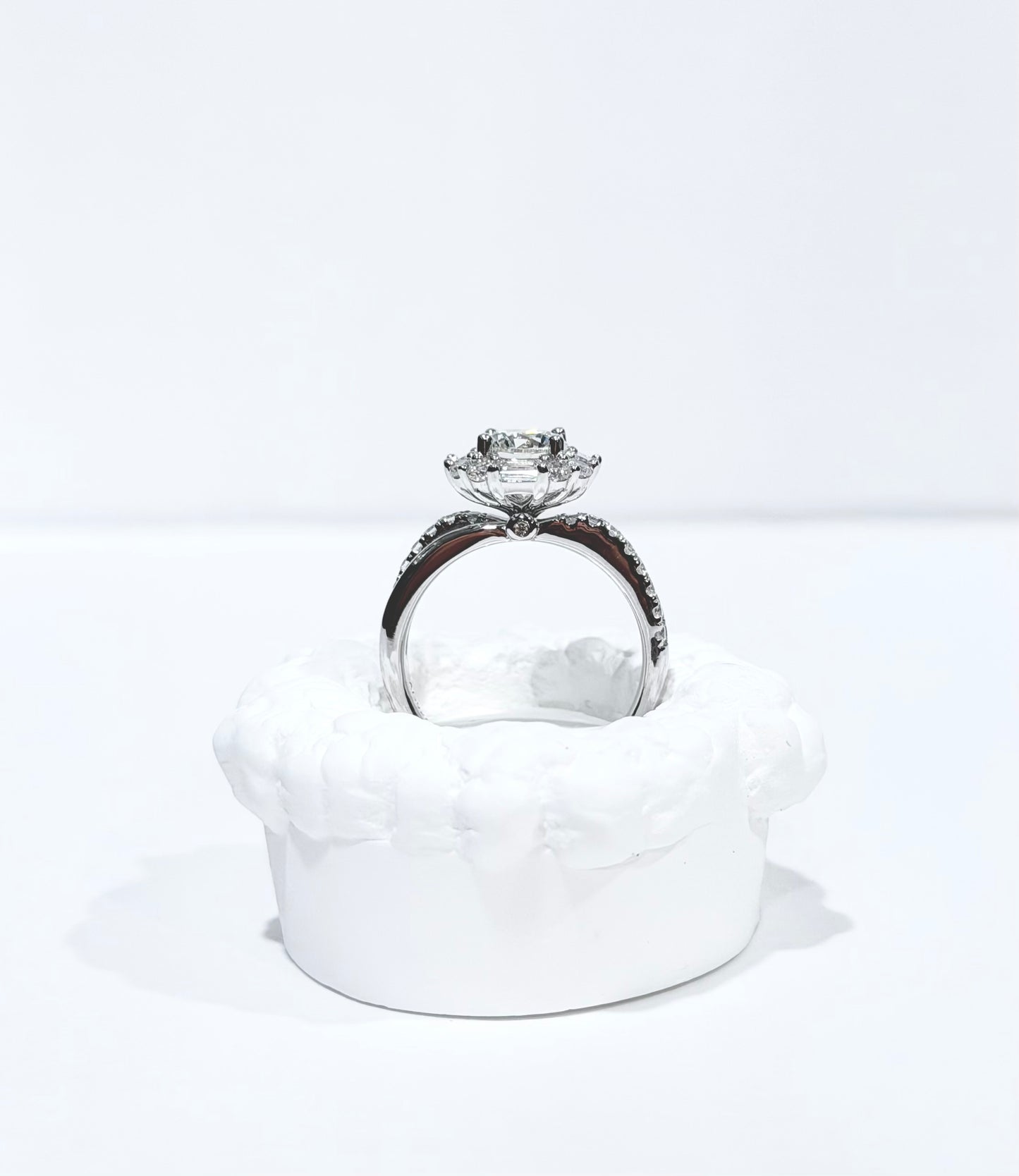 Diamond ring on a white cushion with a white background