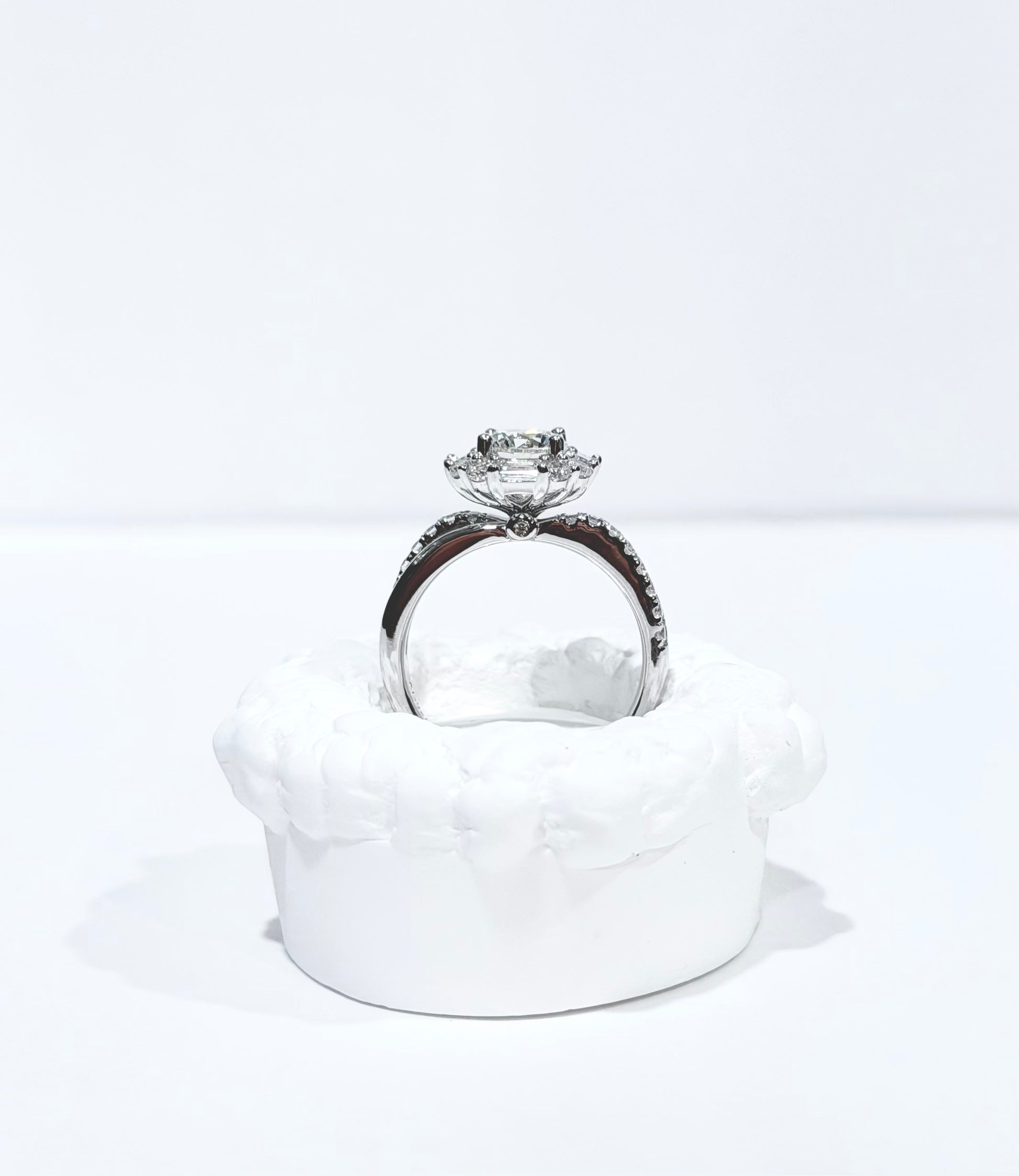 Diamond ring on a white cushion with a white background