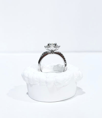 Diamond ring on a white cushion with a white background
