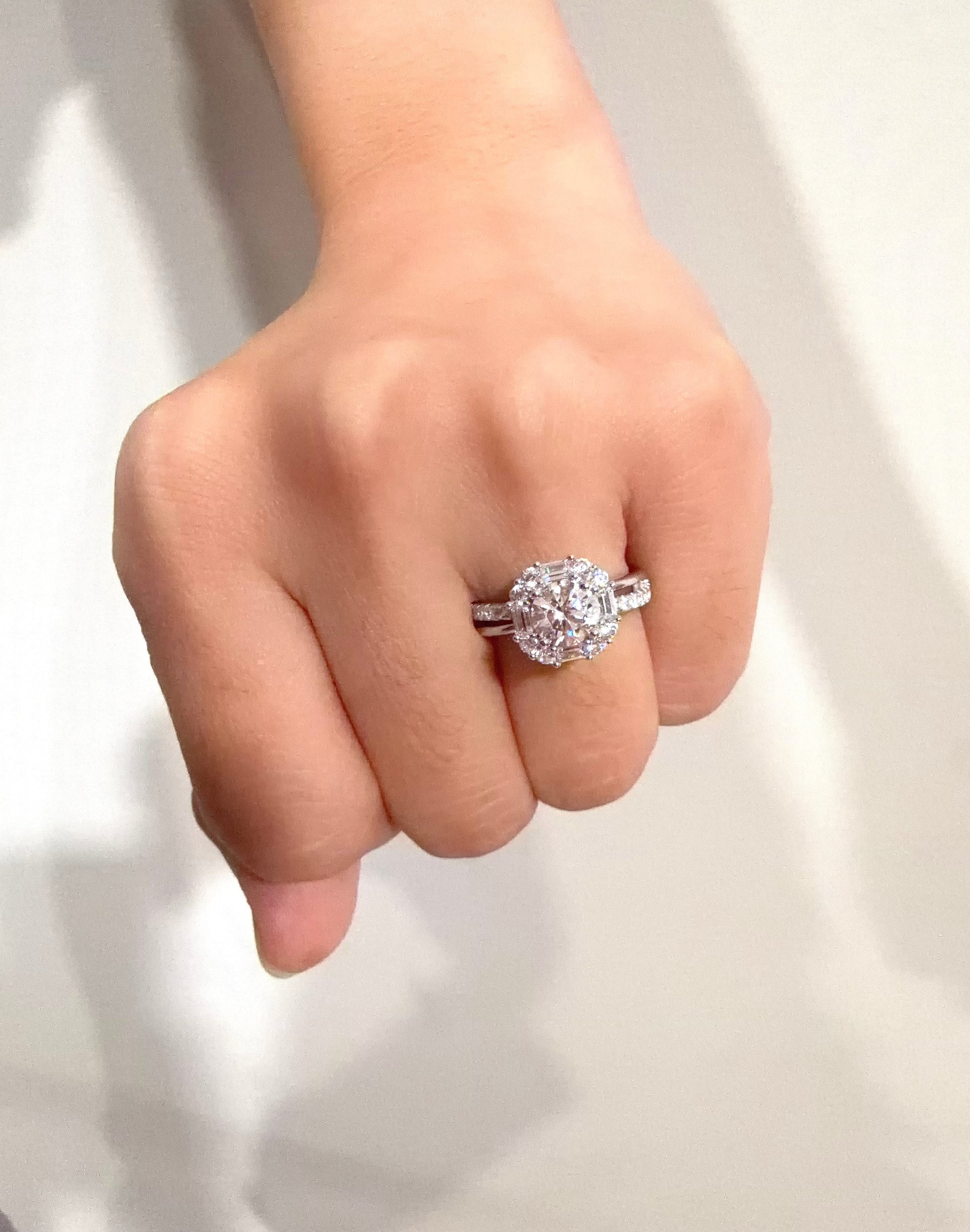 Hand wearing a silver ring with a diamond on a white background
