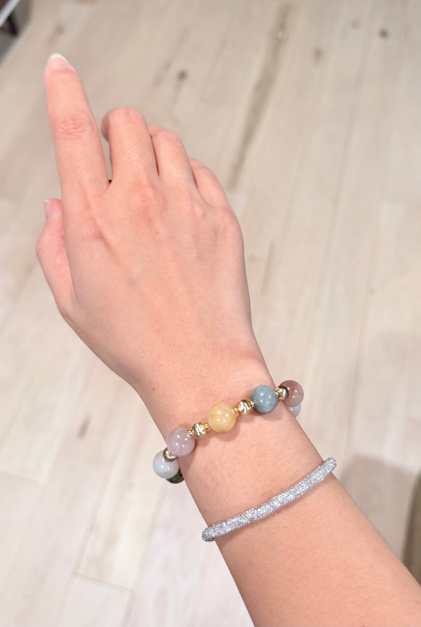 Hand wearing a bracelet with colorful beads on a neutral background