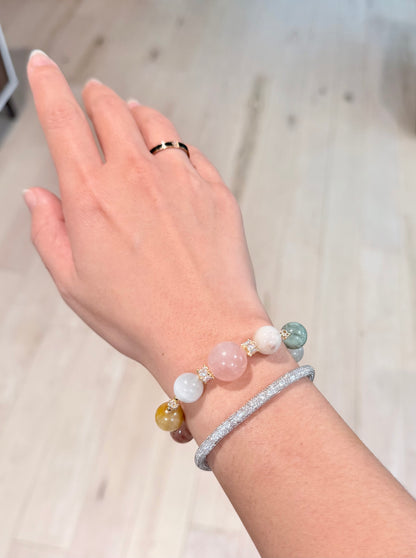 Hand wearing a bracelet with beads on a neutral background