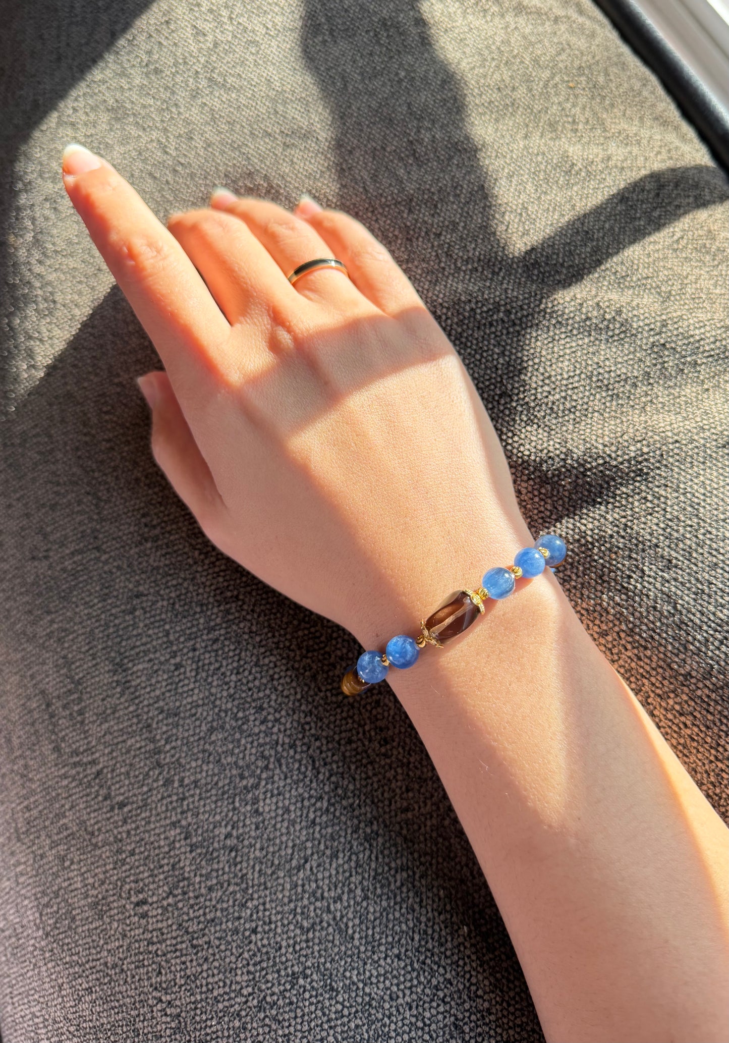 Hand wearing a bracelet with blue beads on a textured surface