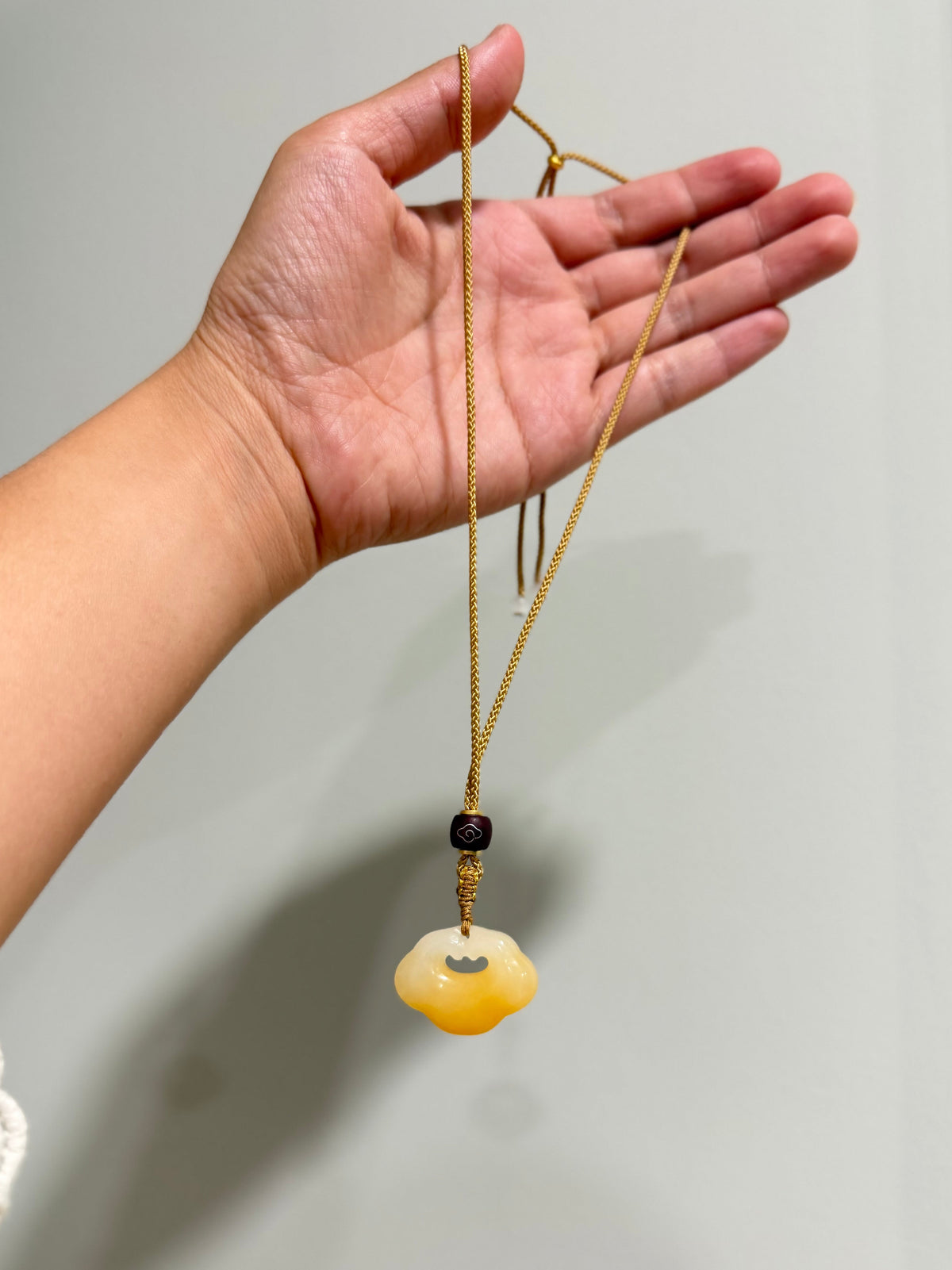 Huanglong jade pendant on an adjustable cord necklace by Lunelle Atelier, showcasing a smooth, polished jade gemstone.