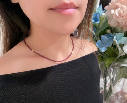 Person wearing a beaded necklace with flowers in the background